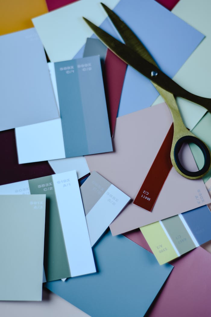 A top view of scattered colorful paint swatches with scissors, perfect for art inspiration.